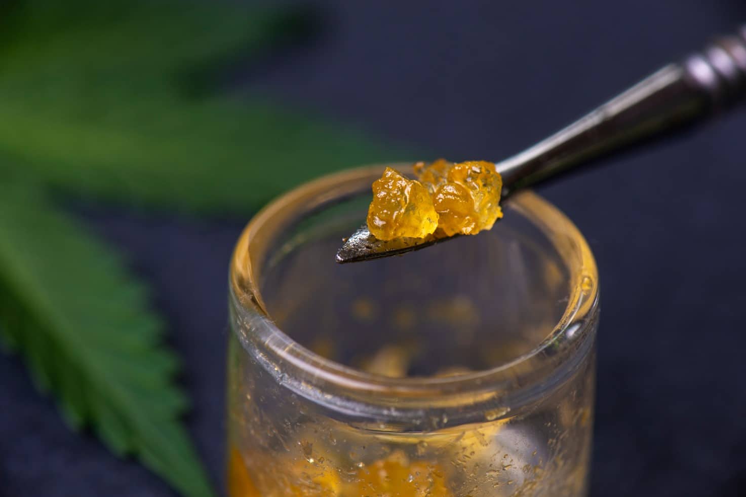 Cannabis concentrate on a dabbing tool in front of a marijuana leaf | Mountain Annie's - Durango Recreational Marijuana Dispensary